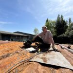 Volunteer with tools on a container roof during the Slice of Hope build