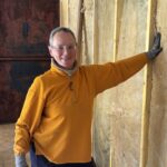 Volunteer fitting insulation between timber studs inside a container